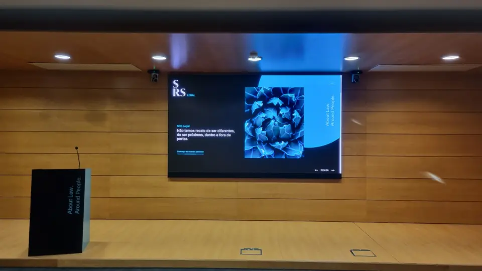 Ecrã LED e púlpito numa sala com parede em madeira